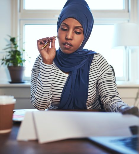 Young Arabic female entrepreneur reading documents in her home office